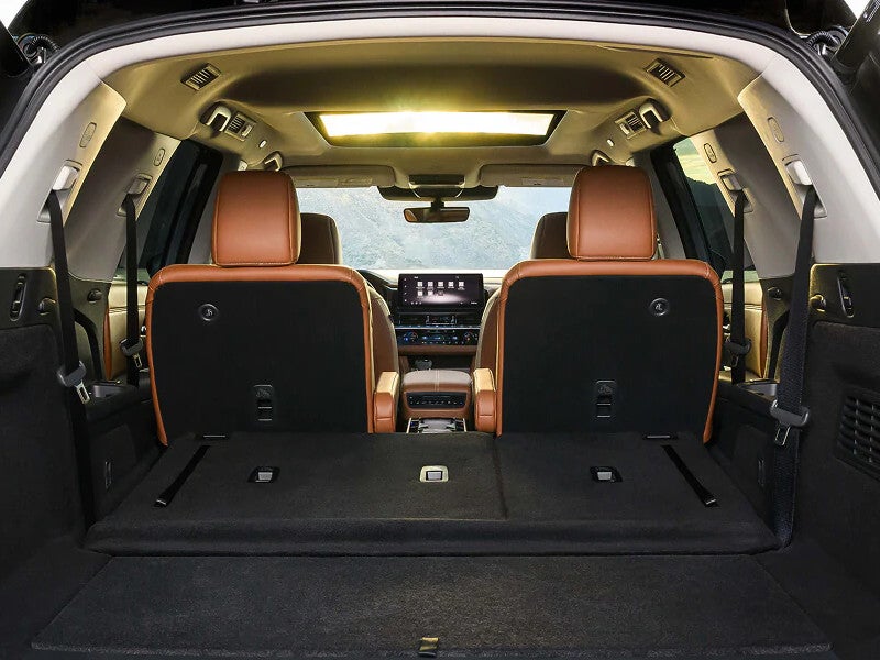 2026 Nissan Pathfinder cargo area with the third row folded flat, showing brown leather seats and a panoramic moonroof
